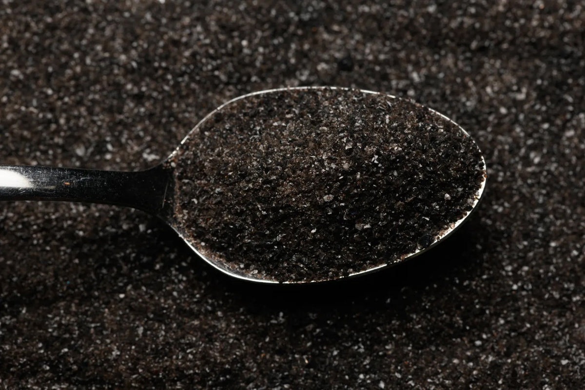 Spoon filled with dark powder on a dark background