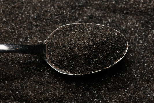 Spoon filled with dark powder on a dark background