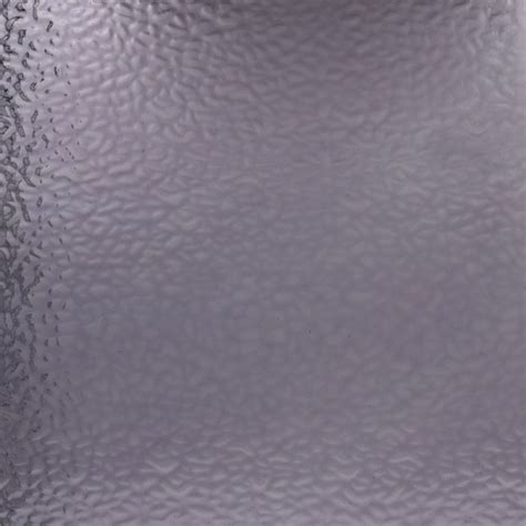 A close-up of a textured frosted glass panel with a subtle wavy pattern and a darker textured edge on the left.