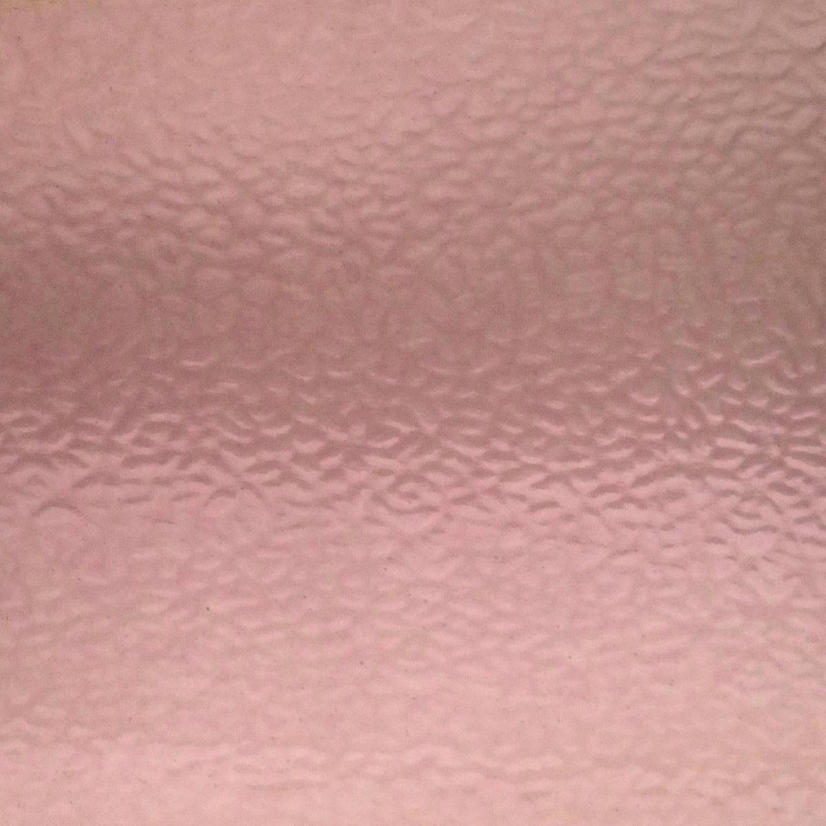 A close-up of a textured pink surface with a subtle hammered or pebbled pattern.
