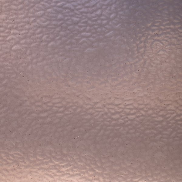 A close-up of a textured, hammered metallic surface with a warm copper or rose-gold tone.