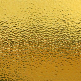 A close-up of a textured gold surface with a fine, hammered or embossed pattern.