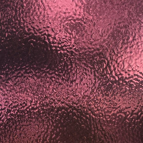 A close-up of a textured, metallic rose pink surface with a wavy, hammered pattern.
