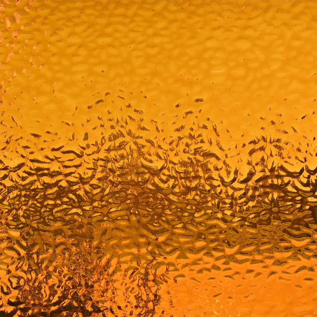 A close-up of textured orange-gold material with a hammered or ribbed surface and darker reflective streaks across the middle.